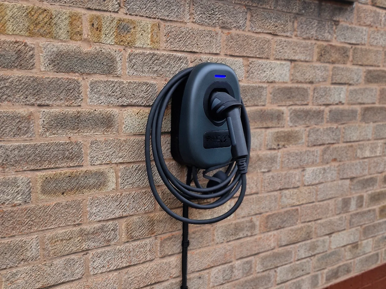 Tethered EV charger mounted beside a driveway in Wakefield by Knox Power & Data, connector holstered and cable neatly coiled