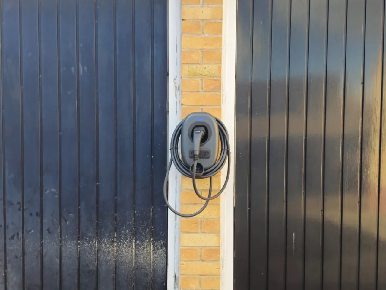 Smart EV charger installed on a garage wall in Wakefield by Knox Power & Data, with a neatly coiled charging cable