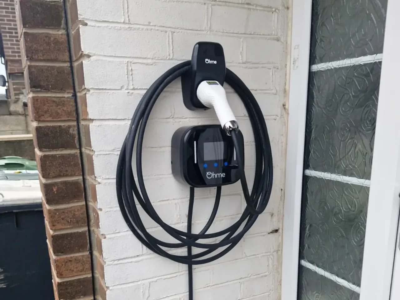 Smart Ohme EV charger fitted on a painted brick wall in Wakefield by Knox Power & Data, with weatherproof cable routing